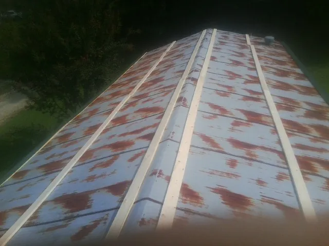 Rusted metal roof panels with new wood purlins before replacement in Kelley