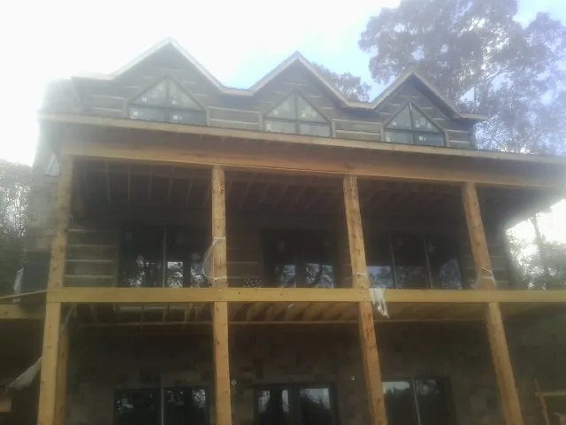 Dormers and porch framing on a large log home under construction — Roof Coating work by our crew in Kelley