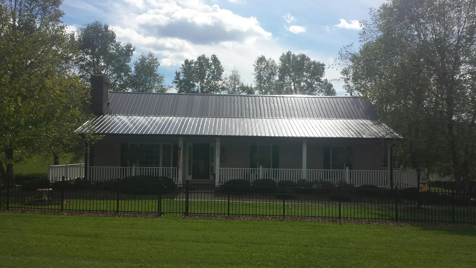 Gray metal roof on a brick ranch with a full width front porch — Gutter Guard Installation work by our crew in Kelley