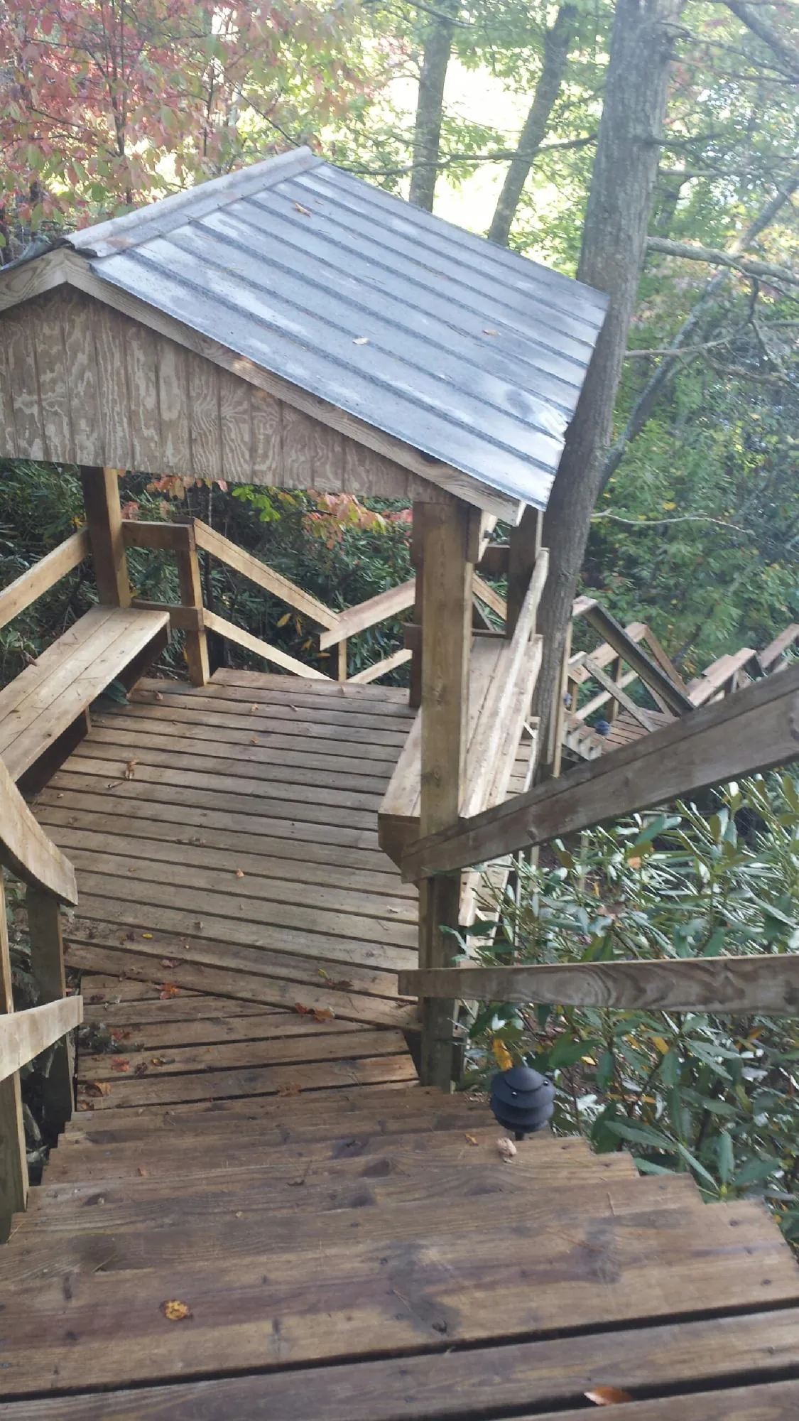 Metal roofed shelter over wooden steps on a wooded walkway — Skylight Repair & Installation work by our crew in Kelley