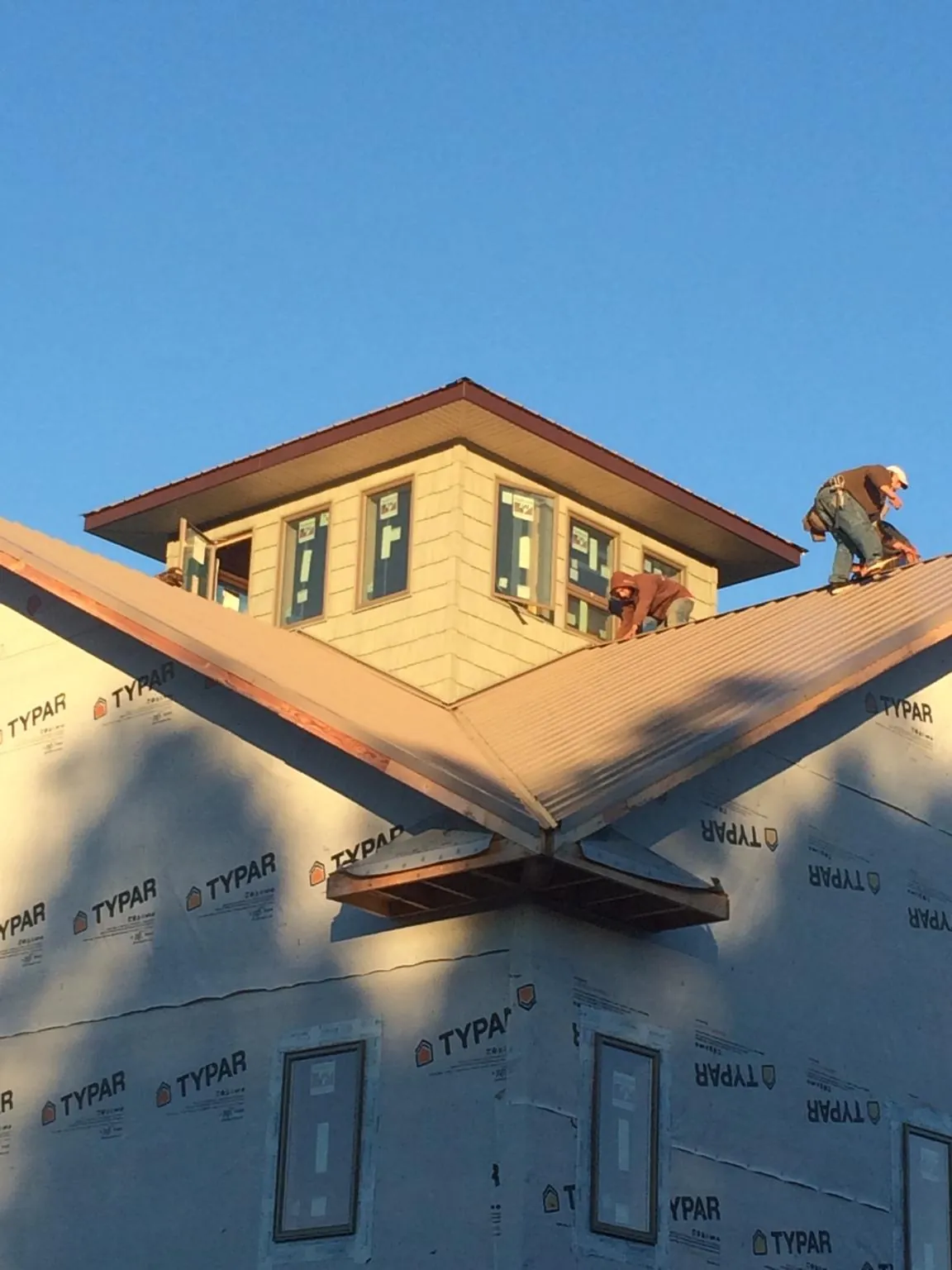 Roofers working around a rooftop cupola on a new metal roof at sunset — Roof Waterproofing in Kelley by Roofing Brothers